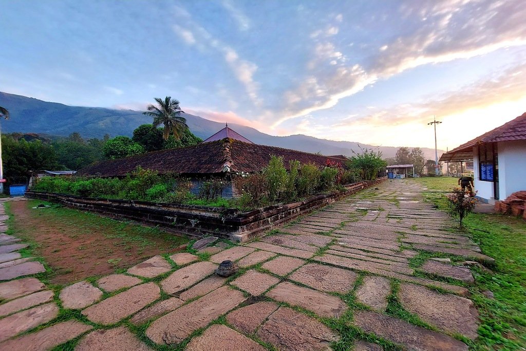 The stone-paved temple ground at Thirunelly, the Brahmagiri hills behind it at dusk